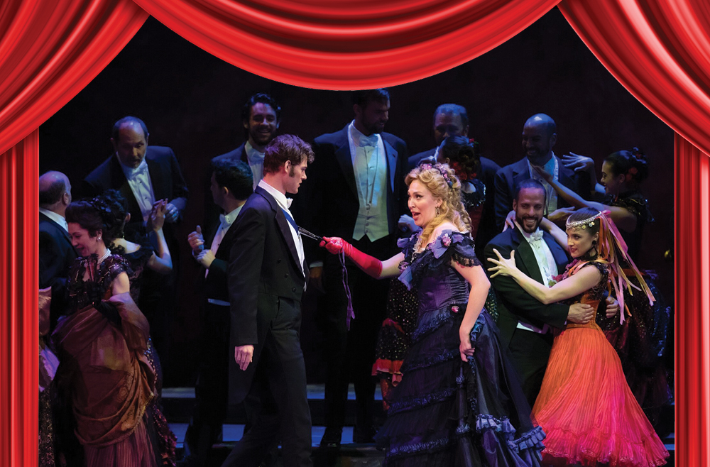 A ballroom scene from the Palm Beach Opera’s production of La Traviata: Natalie Havens is in the center with the cast performing on stage. 